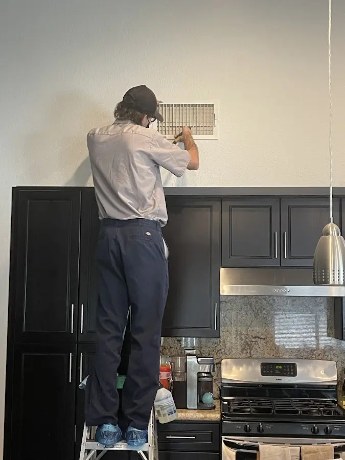 Technician inspecting an air vent during HVAC service in Piscataway